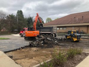 Crane digging up asphalt parking lot