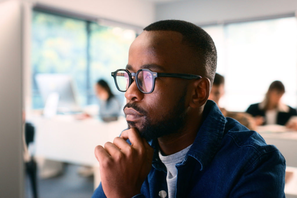 Man sits at computer with screen reflecting in his glasses, reviewing the regulatory environment for credit unions